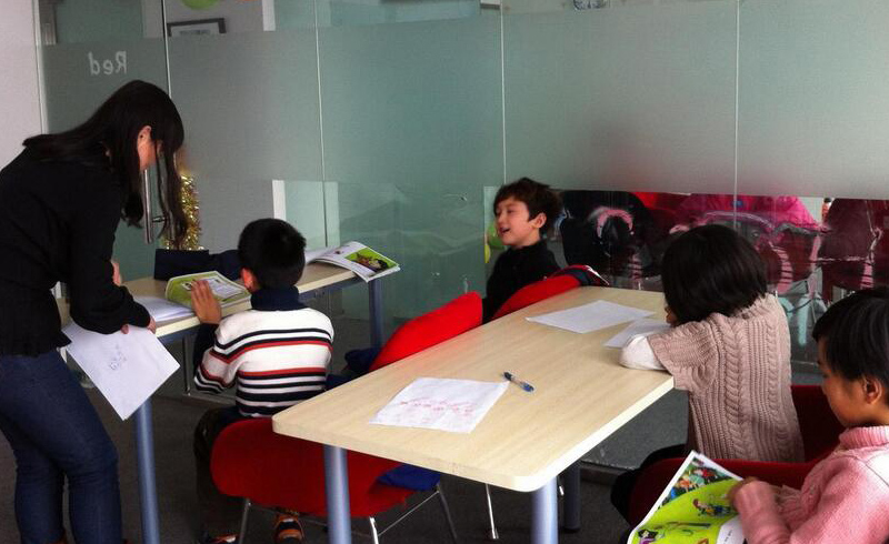 北京新航道优加青少英语_学习中的可爱的学生和现场指导学生的老师