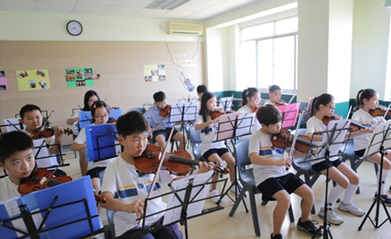北京耀华国际学校_音乐艺术课学习小提琴的学生