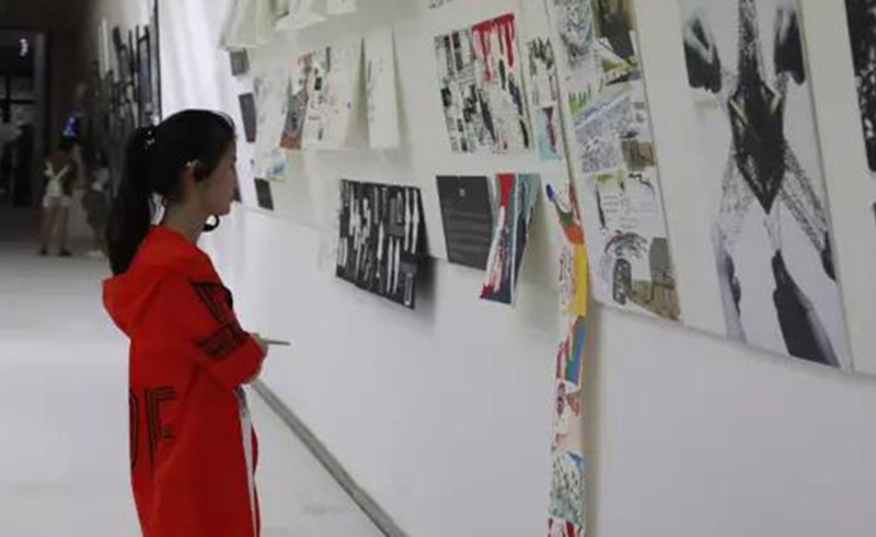 一位学生正在欣赏其他学生贴在墙上的作品