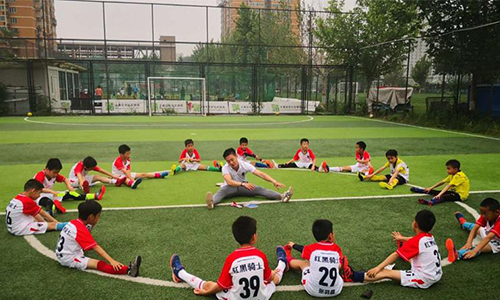 北京红黑骑士青少年足球俱乐部教练和学员一起做游戏